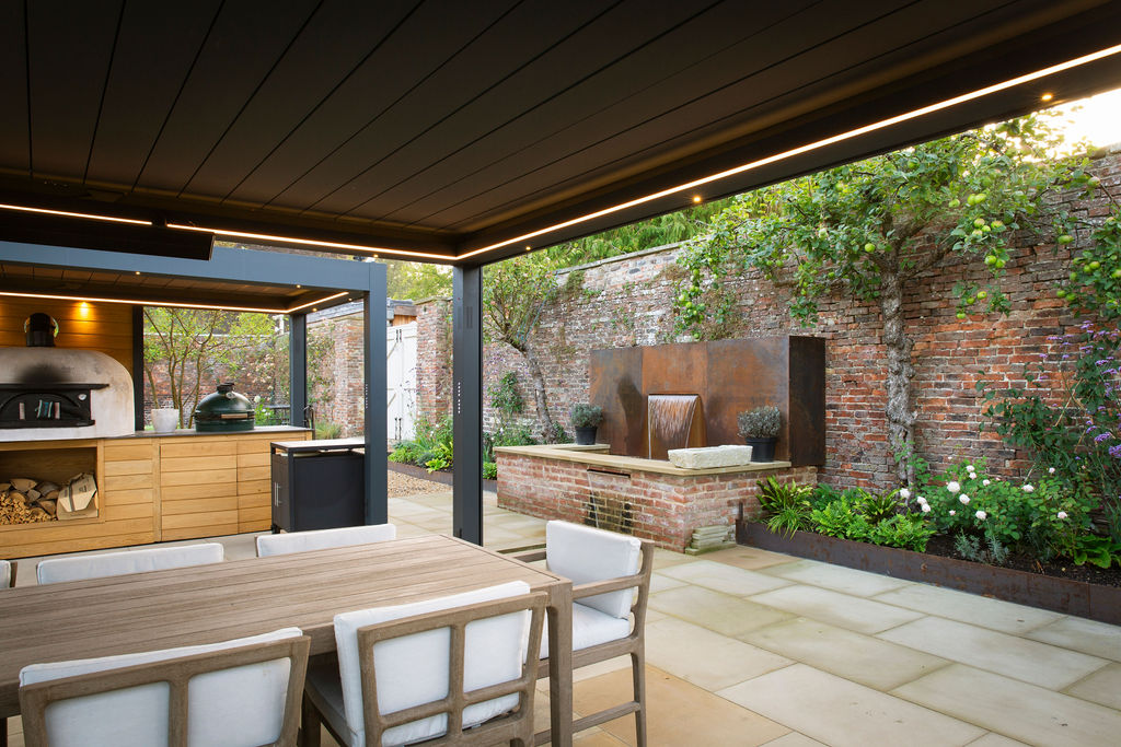 Walled garden with water feature, seating area and shrubbery.