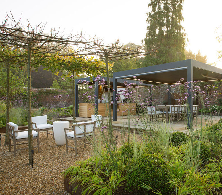 Walled garden with neat hedge, seating area and shrubbery.