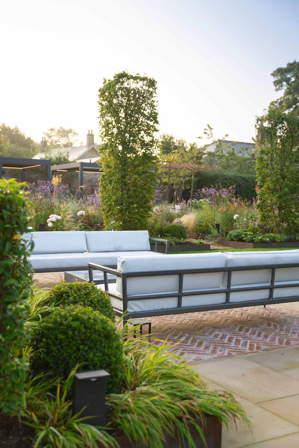 Walled garden with neat hedge, seating area and shrubbery.